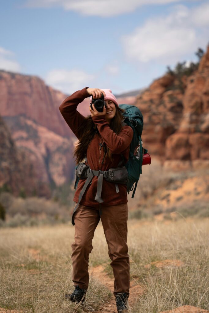 A woman hiker with a backpack captures the majestic Utah landscape with her camera.